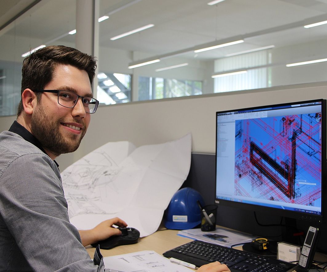 Engineer at CAD workstation with 3D construction drawing of a precast concrete plant on the screen