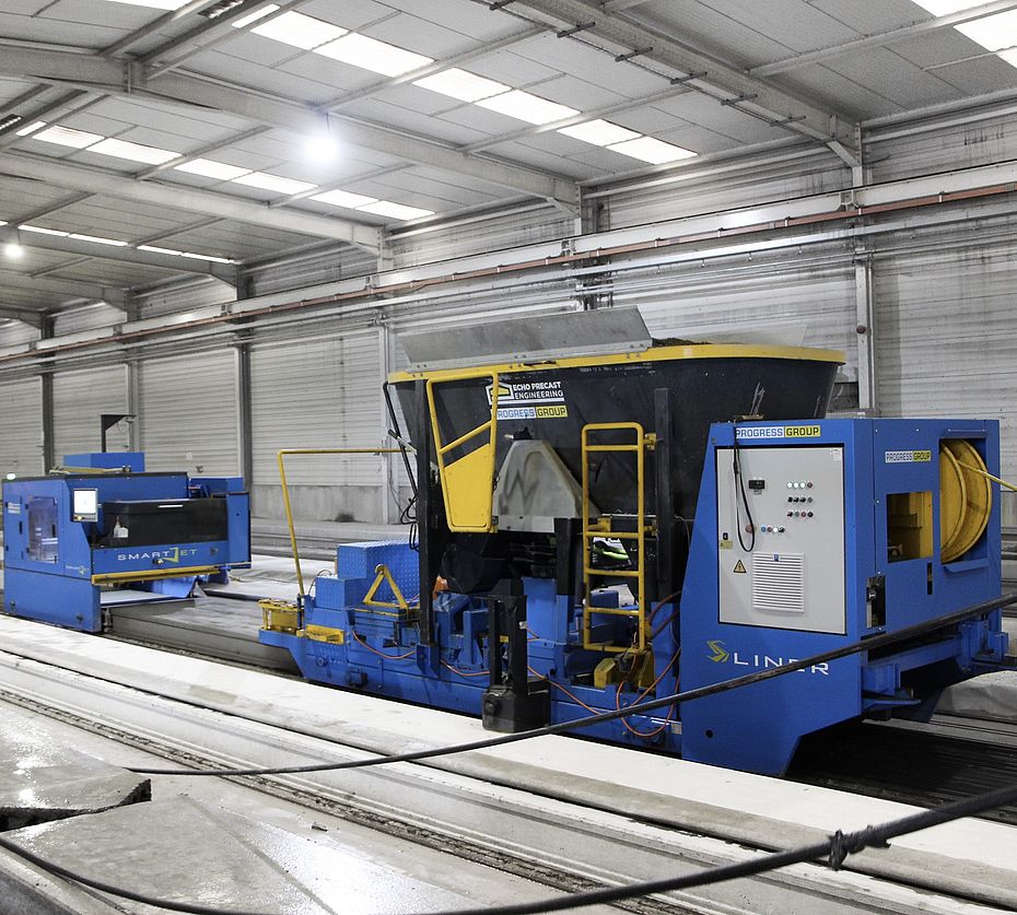 Machine de coffrage glissant S-Liner bleu et jaune produisant des éléments préfabriqués en béton sur bancs de précontrainte