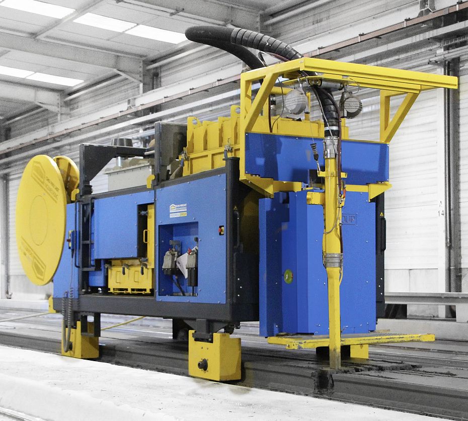 Extrudeuse de dalles alvéolaires bleu et jaune sur bancs de précontrainte dans un hall métallique