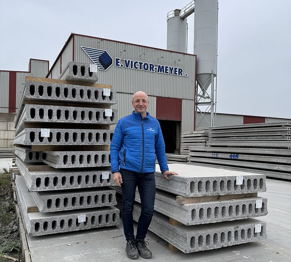 Homme devant des dalles alvéolaires en béton précontraint empilées à l'usine E. Victor-Meyer
